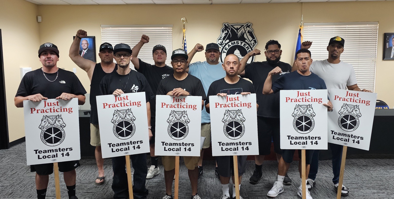 Vestis Las Vegas workers standing together with Teamsters Local 14 picket signs, fists raised in solidarity